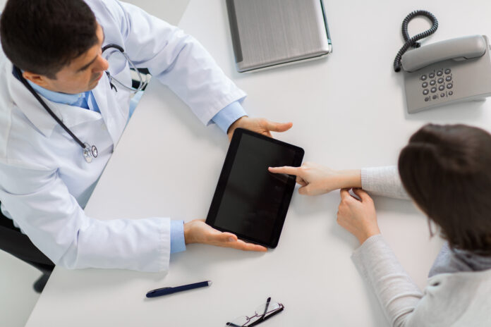 medicine, healthcare and people concept - doctor with tablet pc computer and young woman meeting at hospital